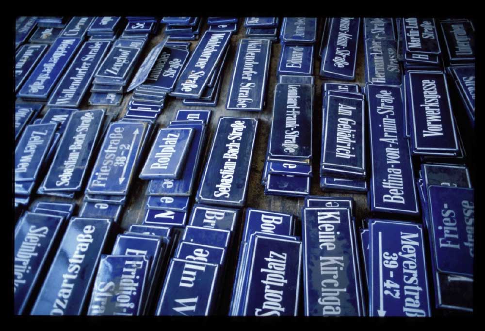 Blue and white very old street signs from Germany laid out on a artist studio flour